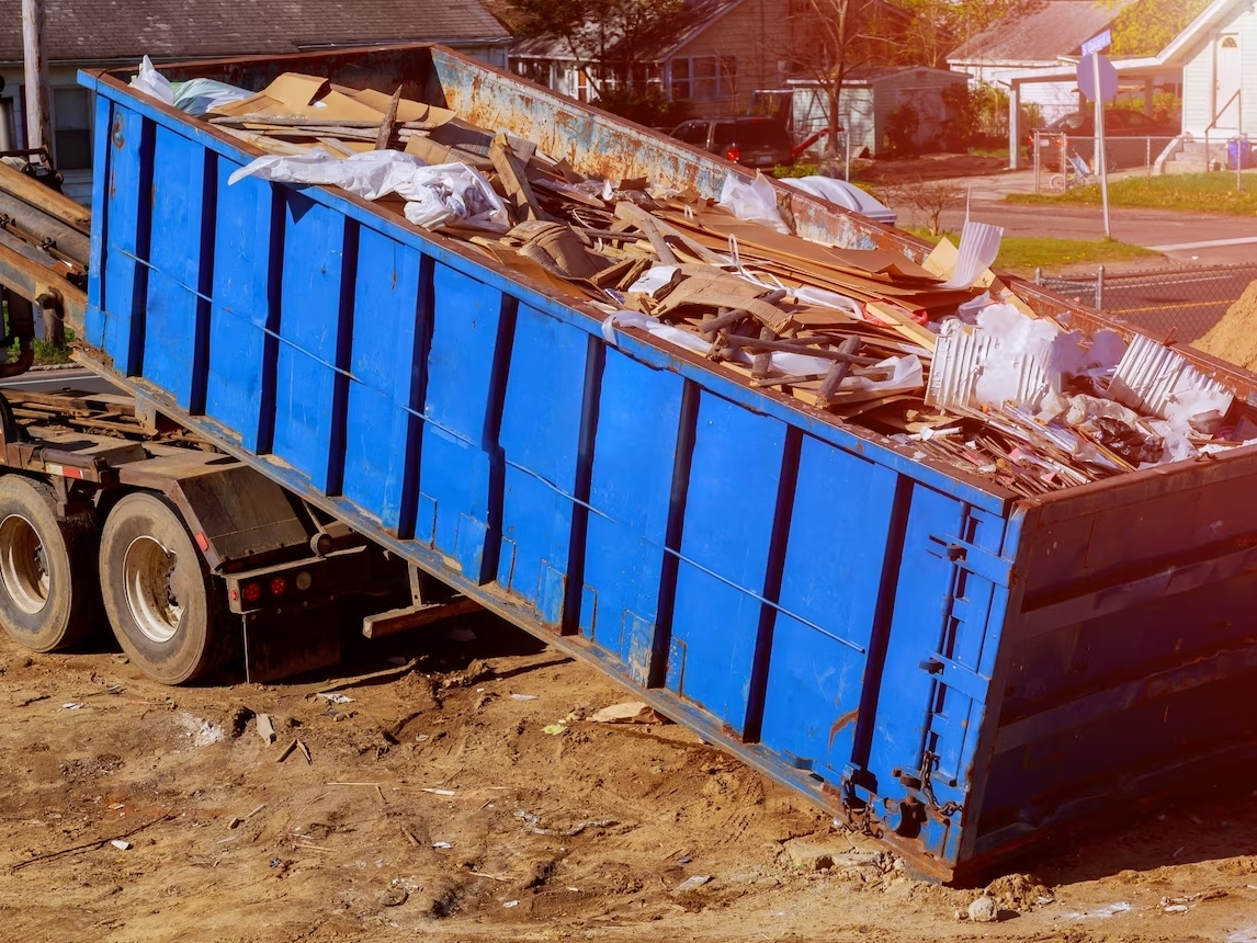 Photographie d'une benne de chantier en train d'être récupérée par un camion de recyclage.