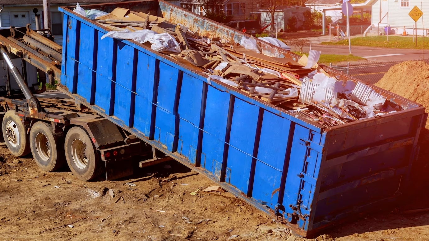 Photographie d'une benne de chantier en train d'être récupérée par un camion de recyclage.