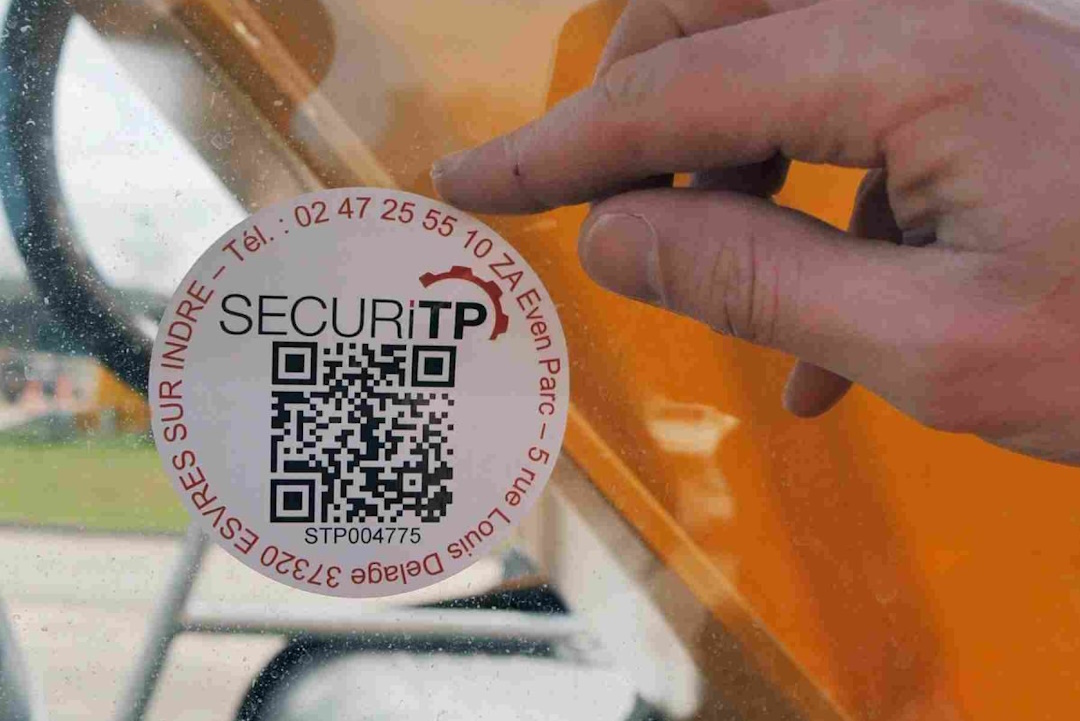 Image de l'auto-collant de contrôle securiTP avec un QRcode en train d'être collé sur une vitre.