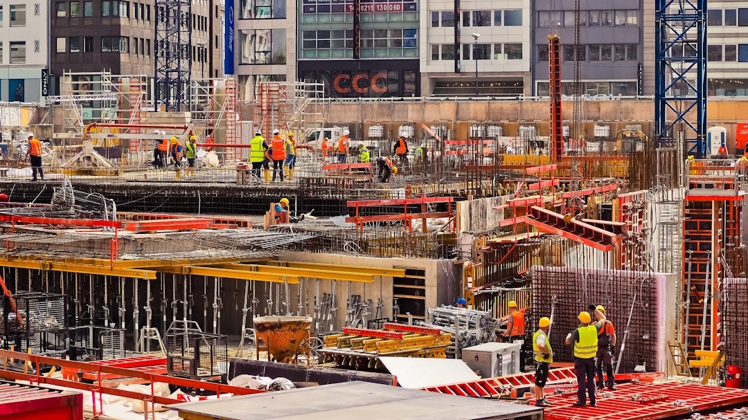 Photo d'un chantier, construction d'un immeuble. On voit tout le matériel et le personnel actif.