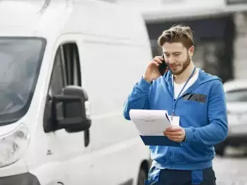 livreur au téléphone et son camion de livraison