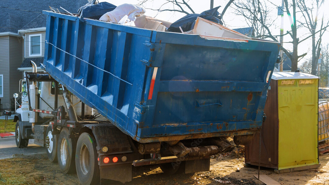 Photo d'un camion de transport de bennes avec une benne chargée en train d'être portée par le camion. Grâce à un bon suivi de benne, la benne récupérée est totalement remplie.