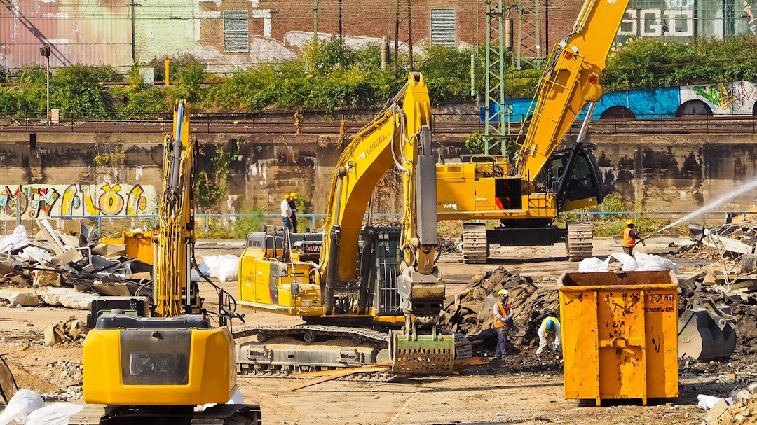 Photo d'un chantier ferroviaire avec 3 tractopelles qui déblaient des déchets de destruction.