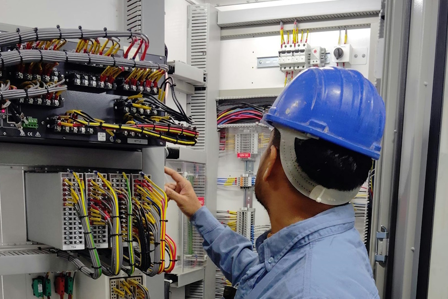 Photographie d'un électricien de l'équipe de maintenance industrielle réalisant une maintenance préventive sur un tableau électrique.